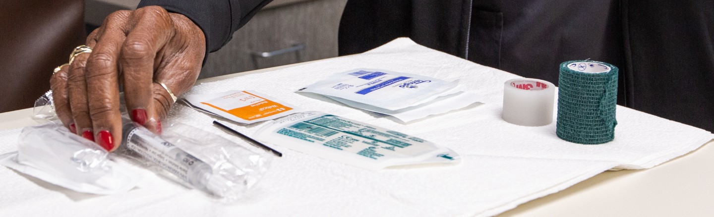 Close up of medical supplies with woman's hand on packaged syringe